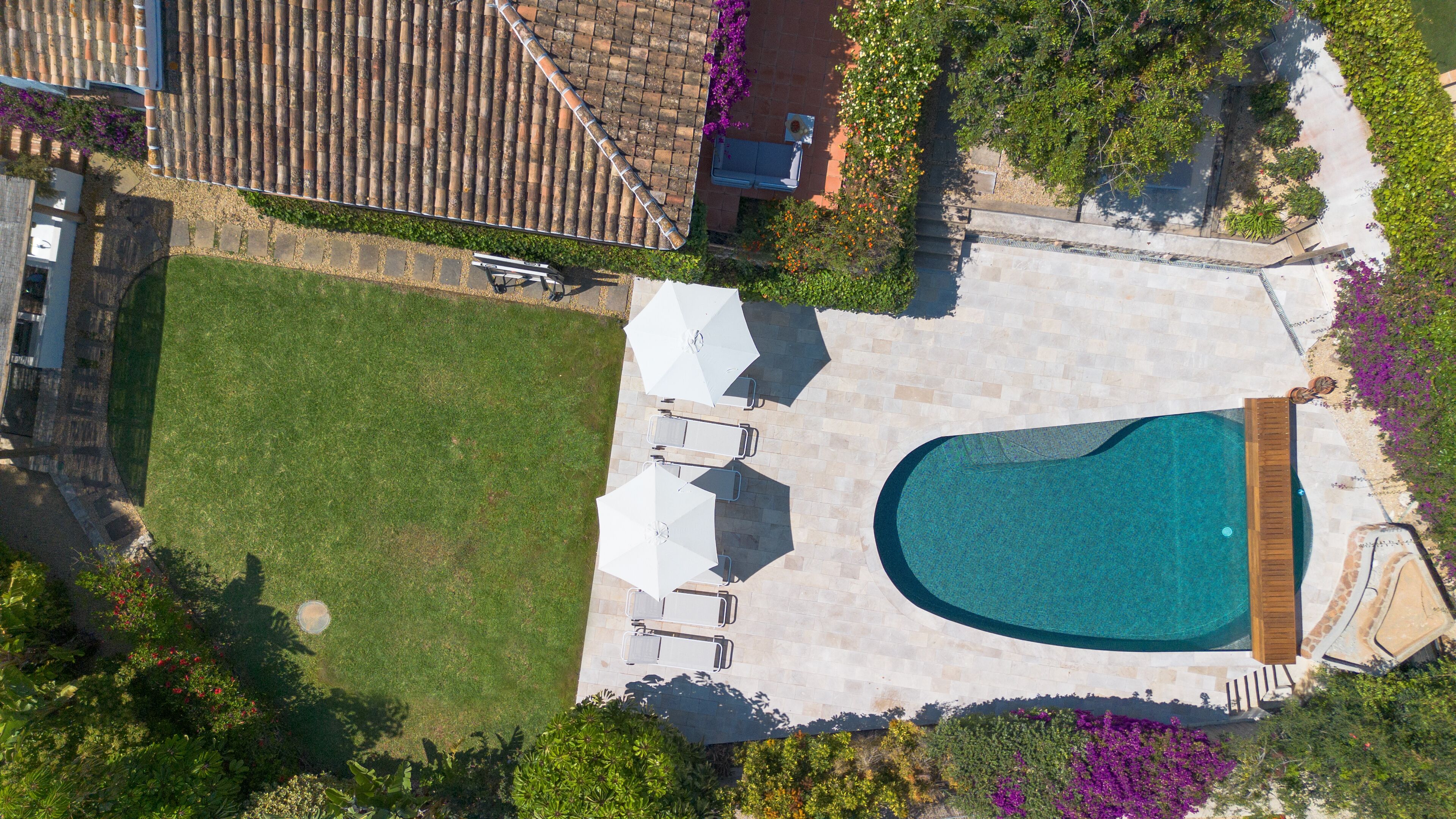 Vista aérea de una propiedad residencial con piscina, muebles de patio y césped.