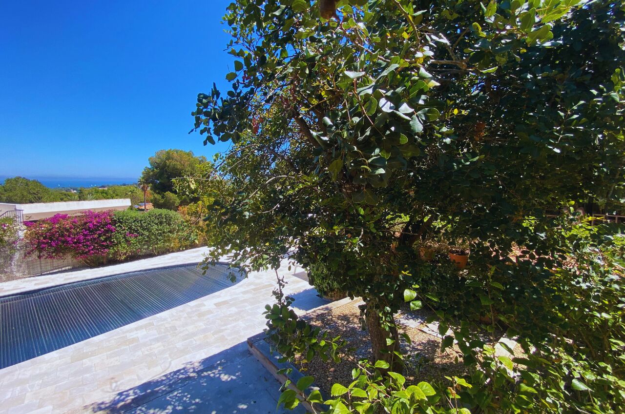 Une piscine offrant une vue dégagée sur l’océan, entourée d’une végétation luxuriante et d’un jardin bien entretenu.