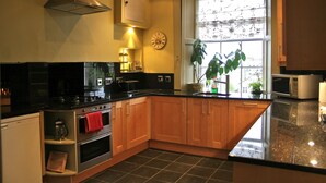 A modern kitchen with wooden cabinets, a stainless steel range hood, a built-in oven, and a microwave.