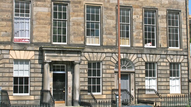 A multi-story stone building with large windows and a symmetrical facade.