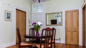 A dining room with a wooden table, four chairs, a vase with flowers, and a mirror on the wall.