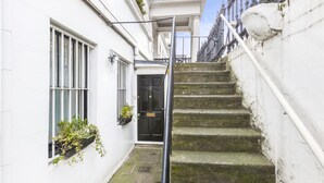 Ein schmaler Gang mit einer Treppe aus Stein, die zu einer schwarzen Tür mit der Nummer 2 führt.