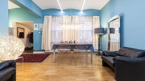 Ein modernes Wohnzimmer mit Essbereich, ausgestattet mit einer Chandelier, einer Couch und einem Tisch mit Stühlen.