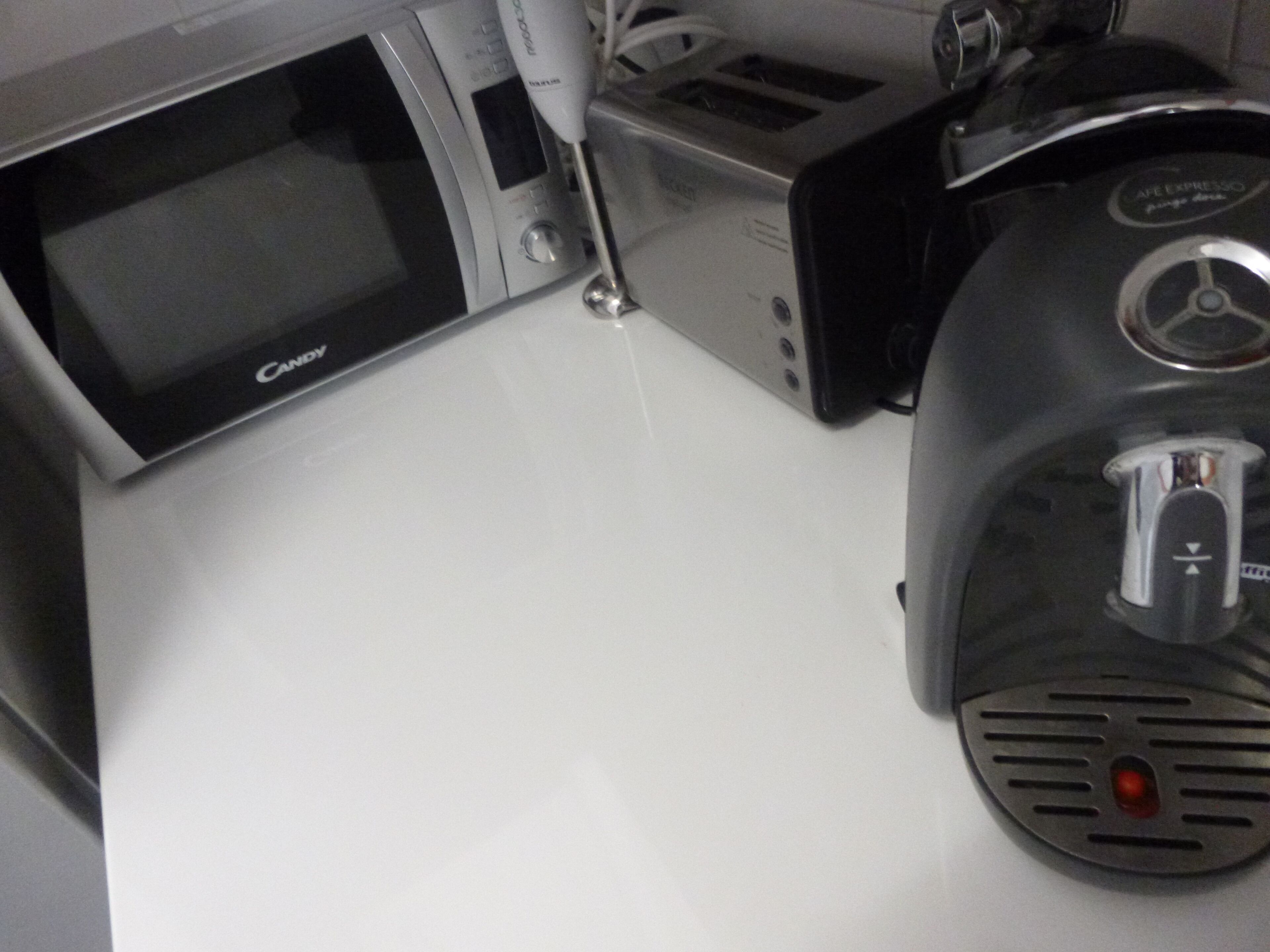 A microwave, a coffee maker, and a toaster on a white countertop.