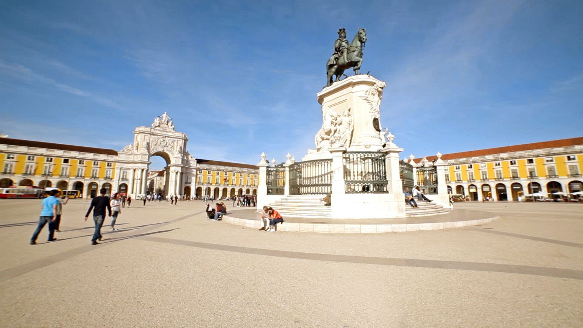 Ein Platz mit einem zentralen Denkmal, einem Torbogen und umgebenden Gebäuden.