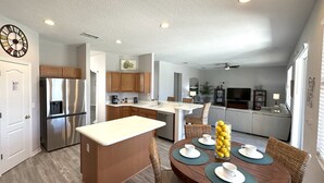 A modern kitchen with a central island, wooden cabinets, and a stainless steel refrigerator.