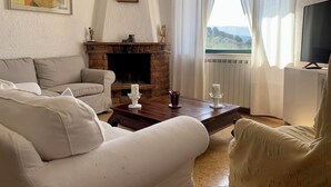 Ett vardagsrum med en öppen spis, en soffa, ett soffbord och en tv.