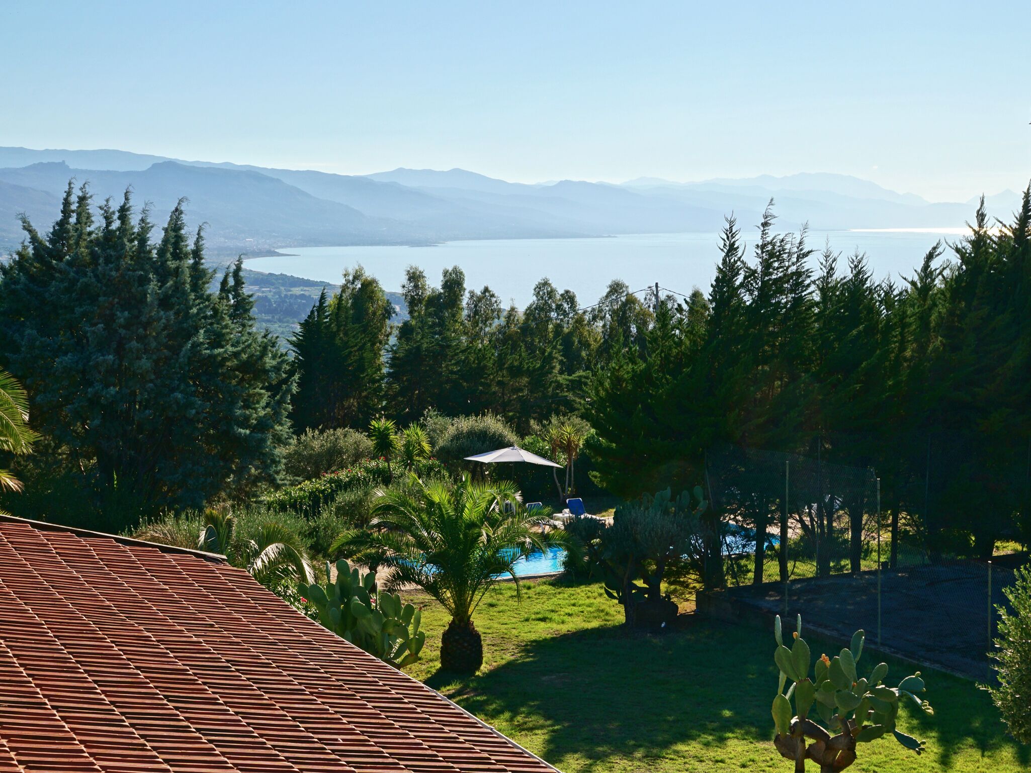 Vista de un paisaje montañoso con una zona de piscina rodeada de abundante vegetación y cactus.