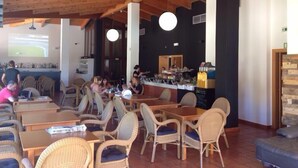 A restaurant with wooden ceiling beams, wicker furniture, and a bar area.