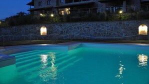 Ein Steinhaus mit Pool, mit einer Steinwand mit Rundbögen und einem umzäunten Bereich.