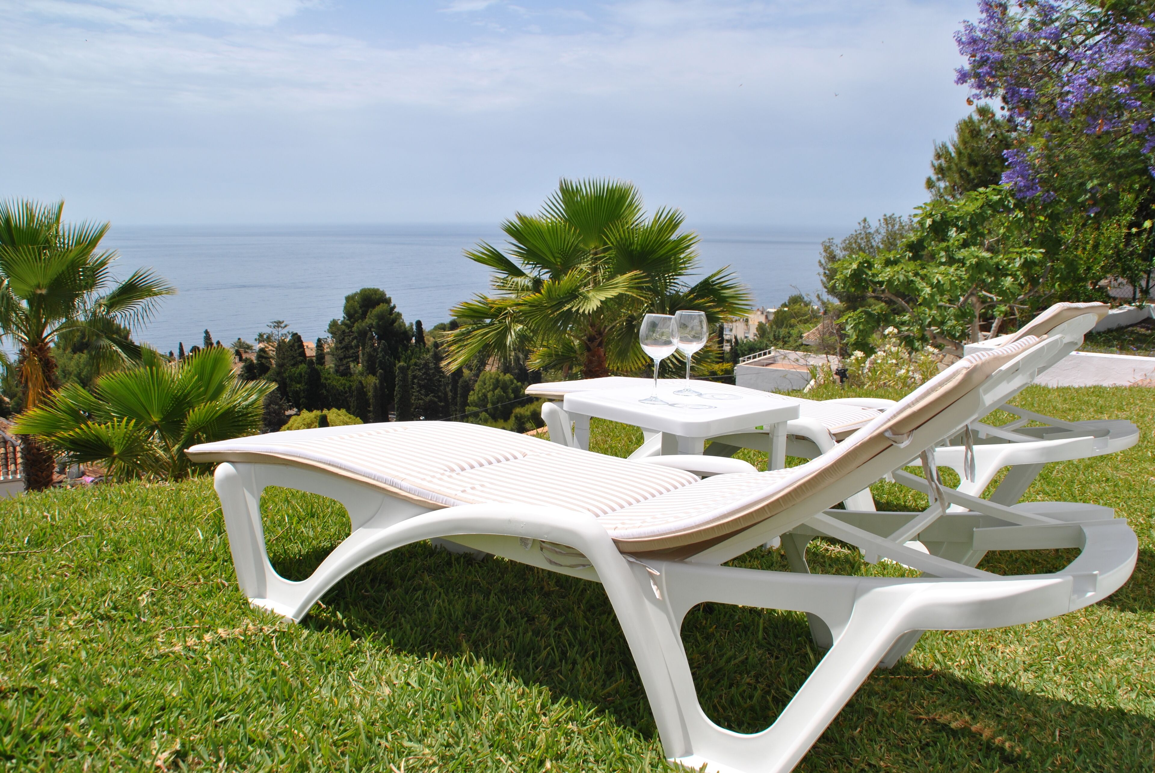 A white outdoor seating area with a view of the sea.