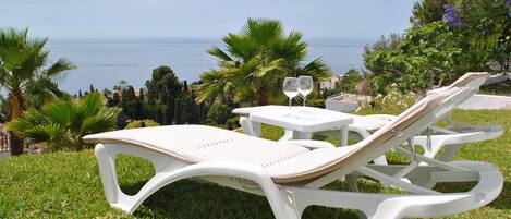 A white outdoor seating area with a view of the sea.