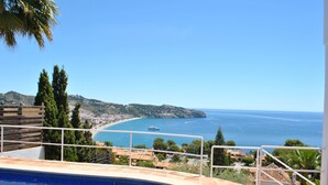 Une piscine avec vue sur la mer et un bateau visible au loin.