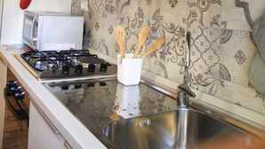 A kitchen with a gas stove, a microwave, and a stainless steel sink. - Holiday Apartment Maison Velia in San Giovanni Colli Albani Appio Latino district (Roma)