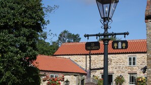A stone building with a red-tiled roof, a sign reading "33 The Green", and flower pots on the ground. - LUXURY 5* GOLD CONVERTED BARN WITH HOT TUB.TRADITIONAL VILLAGE NORTH OF  LINCOLN (Lincoln)