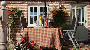 A patio with a table and chairs under a large umbrella, surrounded by potted plants and flowers. - LUXURY 5* GOLD CONVERTED BARN WITH HOT TUB.TRADITIONAL VILLAGE NORTH OF  LINCOLN (Lincoln)