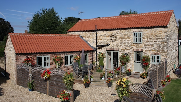 A stone building with a red-tiled roof, a wooden fence, and potted flowers. - LUXURY 5* GOLD CONVERTED BARN WITH HOT TUB.TRADITIONAL VILLAGE NORTH OF  LINCOLN (Lincoln)