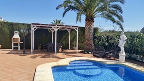 A pool area with a pergola, outdoor seating, and a statue.