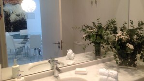 A bathroom with a large mirror, a sink, a toilet, and a vase with flowers. - Unmatched Luxury next to the  Cathedral - Valencia (València)