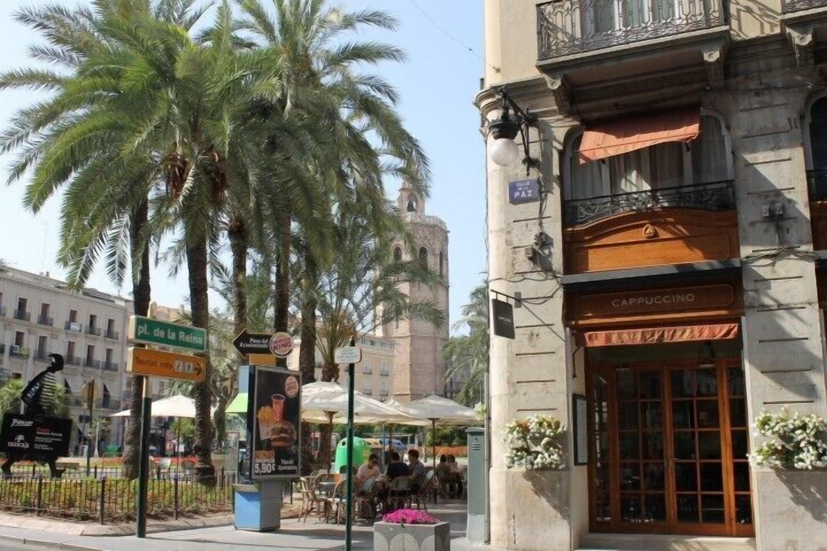 A street scene with a café named 'Cappuccino' and a sign for 'Pl. de la Reina'.