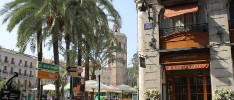 A street scene with a café named 'Cappuccino' and a sign for 'Pl. de la Reina'.