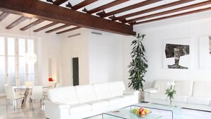 A modern living room with a white sofa, glass coffee table, and a dining area with a white table and chairs. - Unmatched Luxury next to the  Cathedral - Valencia (València)