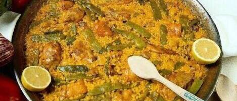 Un grand plat rempli d’un plat de riz garni de tranches de citron, entouré de divers légumes.