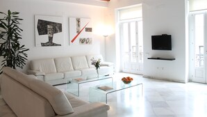 A modern living room with a white sofa, a glass coffee table, and a TV mounted on the wall. - Unmatched Luxury next to the  Cathedral - Valencia (València)