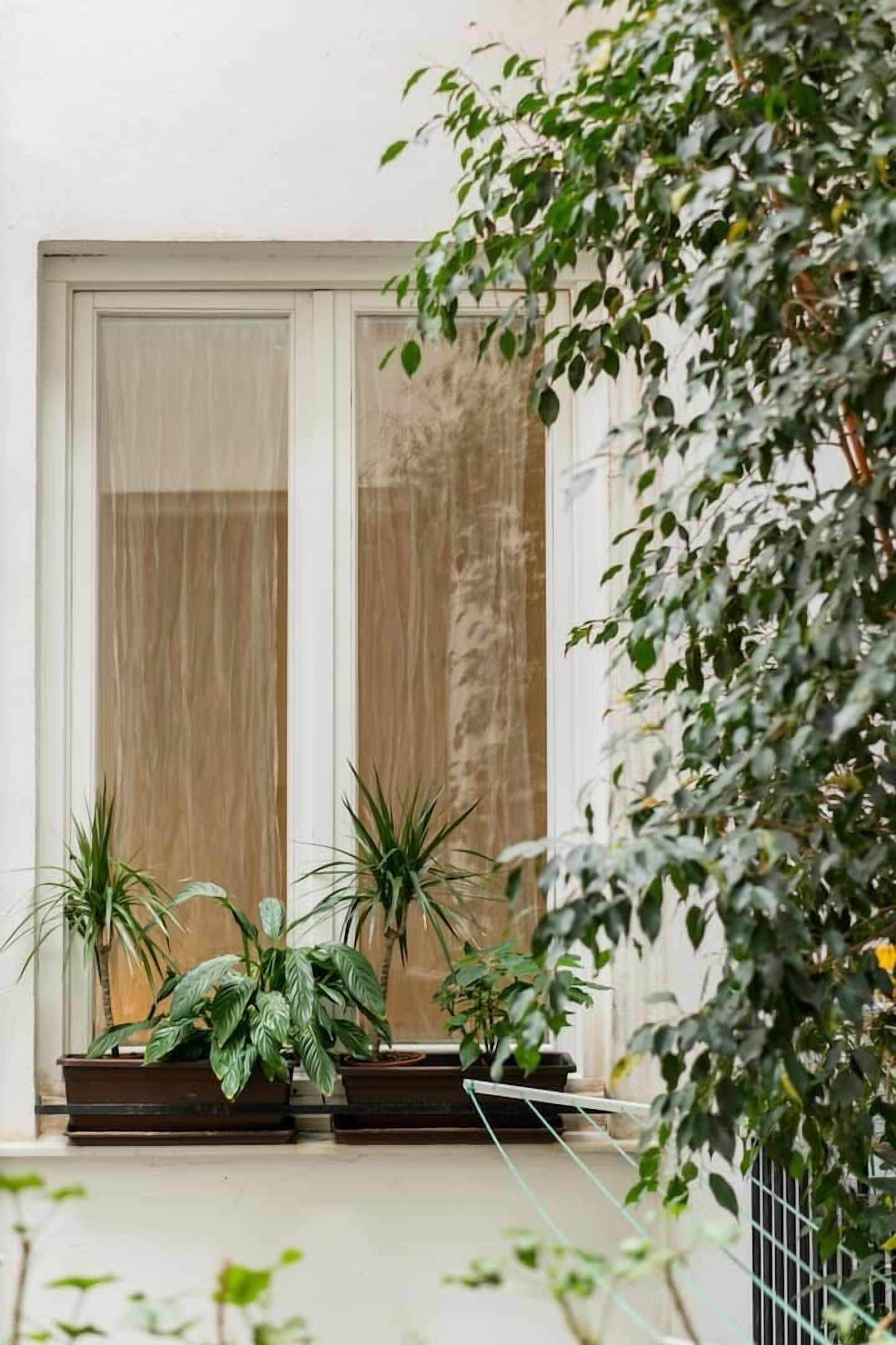 Ein Balkon mit Blumentöpfen und einer Schiebeglastür.