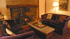 Una sala de estar acogedora con chimenea de piedra, un conjunto de sofás y una lámpara.
