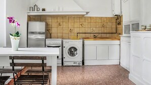 Une cuisine compacte équipée d’un réfrigérateur, d’un lave-linge et d’un évier.