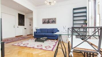 Un salon moderne avec un canapé bleu, une table basse en verre et un tapis à motifs.
