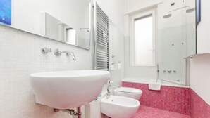 A modern bathroom with a white sink, a bidet, and a shower. - Petrella (Milano)
