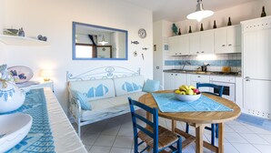 Una cocina moderna con armarios blancos, una mesa de comedor con un mantel individual azul y un sofá azul y blanco.