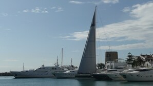 A marina with several yachts docked, a clear sky, and buildings in the background. -  Semi-secluded 3 Bed, 2 bath Tranquil Family Villa with Pool & Gardens  (Estepona)