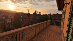 Balcón con barandilla de piedra que da a una zona residencial al atardecer.