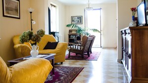 Una sala de estar con un sofá amarillo, una silla de madera, una mesa baja y un mueble para televisor.