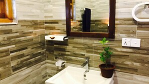 A bathroom with a white sink, a mirror, a towel rack, a soap dispenser, and a potted plant. - Cozy Bay (Arugam Bay)