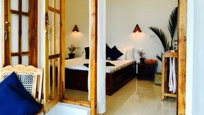 A room with a bed, a wooden chair, a small table, and a potted plant. - Cozy Bay (Arugam Bay)