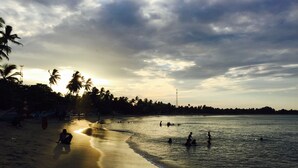 A beach with palm trees, a sandy shore, and calm water. - Cozy Bay (Arugam Bay)