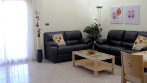 A modern living room with two black leather sofas, a glass coffee table, and a potted plant. - Beautiful, double BEACH FRONT Penthouse, Breathtaking View, Wi-Fi, SAT TV, Pool (San Javier)