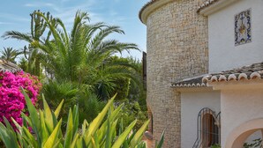 Um edifício com fachada de pedra, varanda com grades de ferro forjado e janela com grade metálica decorativa.