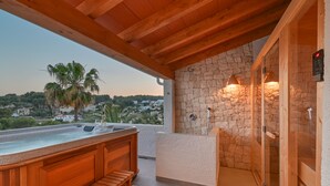 Uma banheira de hidromassagem com bancos de madeira, parede de pedra e compartimento de chuveiro em pedra.