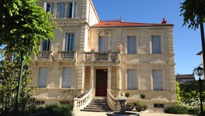 A two-story building with a red-tiled roof, a central entrance with a staircase, and a small fountain in the courtyard. - House / Villa - Saint-Rémy-de-Provence (Saint-Rémy-De-Provence)