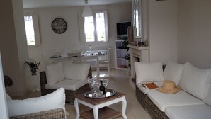 A living room with a white sofa, a wicker coffee table, and a dining area with a table and chairs. - House / Villa - Saint-Rémy-de-Provence (Saint-Rémy-De-Provence)