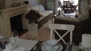 A dining area with a fireplace, white furniture, and a view of the outdoor patio. - House / Villa - Saint-Rémy-de-Provence (Saint-Rémy-De-Provence)
