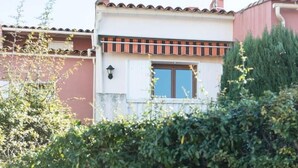 Un bâtiment à deux étages, doté d’une façade rouge et blanche, d’un toit en tuiles et d’une fenêtre avec des volets.
