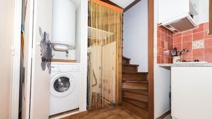 Un espace buanderie comprenant un lave-linge, une porte en bois et une cuisine avec un dosseret carrelé.