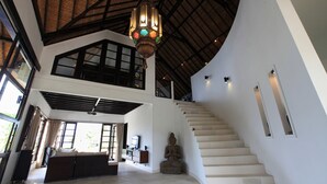 Un interior espaiós amb un sostre alt, una escala i una finestra gran.