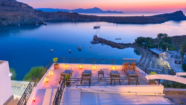 A terrace with sun loungers and a view of a calm sea at sunset. - Brand New!!! Lindos shore Superior Studio just above Lindos main beach !!! (Rhodes)